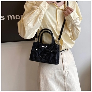 Détail du sac plissé noir avec nœuds perlés et bandoulière réglable pratique