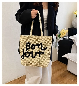 Détail du sac cabas en paille tissée avec broderie Bonjour et texture crochetée