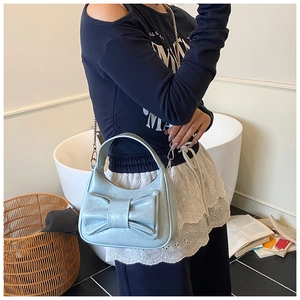 Détail du sac croissant bleu clair avec grand nœud et fine bandoulière en chaîne