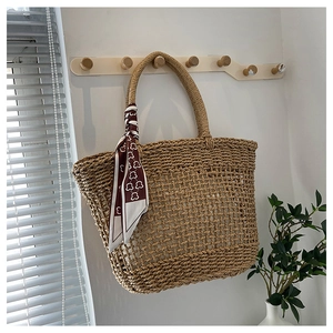 Detail of hand-woven straw tote bag featuring a red and white geometric silk scarf accent