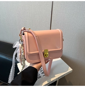 Pink minimalist crossbody bag featuring golden buckle and elegant floral lace charm