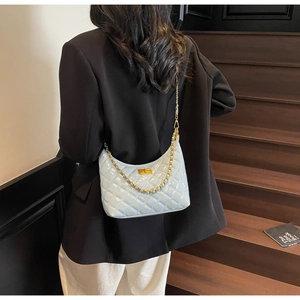 Detail of mint green quilted leather underarm bag with gold chain and turn-lock closure