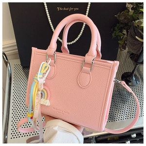 Detail of pink lychee leather handbag with rainbow charm and fashion bags text logo