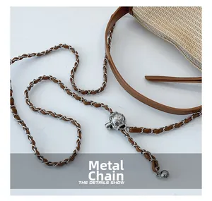 Close-up of hardware chain with spherical metal buckle on straw woven handbag