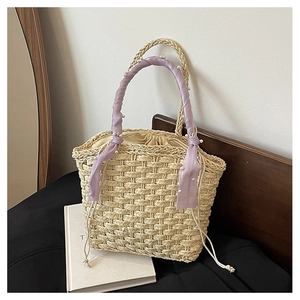 Detail of beige straw bucket bag featuring pearl accents and a lilac silk scarf handle