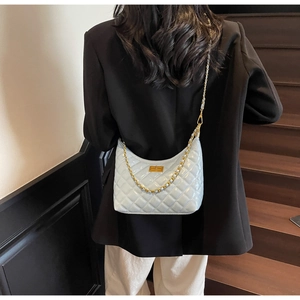 Detail of light blue quilted chain bag with gold metal lock on female model