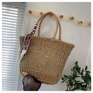 Close-up of hand-woven straw tote bag featuring hollow-out diamond patterns and silk scarf