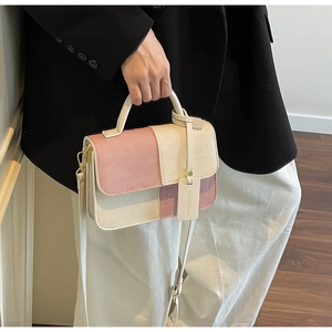 Detail of pink and beige woven crossbody bag with gold hardware and leather strap