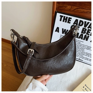 Detail view of dark brown crescent moon bag with textured leather and silver hardware