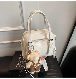 Dettaglio borsa a bauletto in pelle cerata bianco panna con fibbie argentate e orsetto
