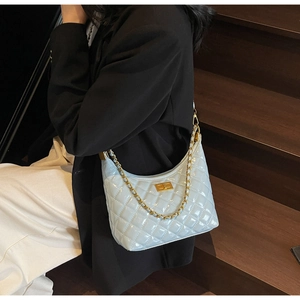 Close-up of light blue patent leather hobo bag with quilted pattern and gold chain strap