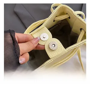 Detail of light yellow pebble leather bucket bag with silver magnetic snap and lining