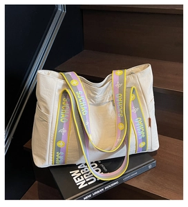 Close-up of minimalist tote bag with colorful striped shoulder strap and side pockets
