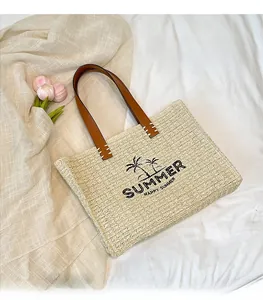 Close-up of straw tote bag with palm tree embroidery and brown leather straps