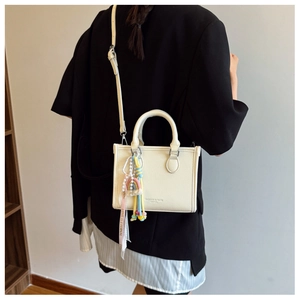 Detail of cream white lychee grain tote bag with rainbow charms and elegant pink ribbon