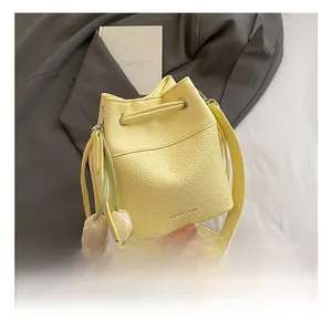 Detail of yellow pebbled leather bucket bag with drawstring and white tulip charm