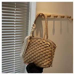 Close-up of woven straw bucket bag with pearl scarf accessory on wooden hook