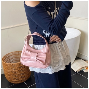 Vue détaillée du sac hobo rose brillant avec un grand nœud et une poignée supérieure