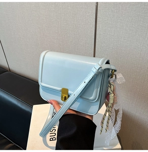 Detail of light blue crossbody bag with gold lock and lace charm accessory