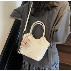 Dettaglio borsa a secchiello bianco crema in pelle con ciondolo orsetto e foulard
