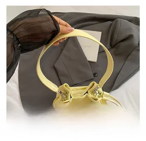 Close-up of light yellow bucket bag with drawstring closure and lychee grain leather texture