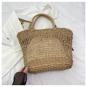 Detailed view of hollow-out woven tote bag with thick handles on a white fabric surface