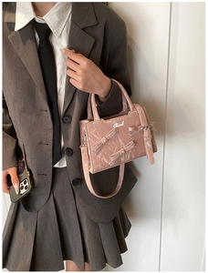 Détail d'un sac à main rose brillant avec nœuds 3D et logo de marque argenté