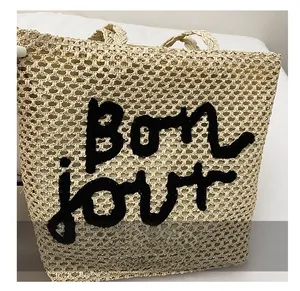 Détail du cabas en paille beige avec broderie Bonjour et texture de tissage ajourée