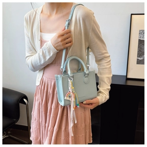 Detail of light blue pebble leather handbag with rainbow tassel and silver hardware