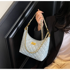 Detail of light blue quilted underarm bag with gold chain strap and metal turn-lock closure