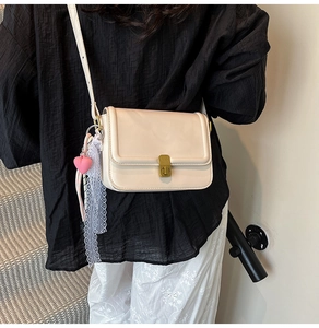 Detail of beige rectangular crossbody bag with vintage metal lock and lace heart charm