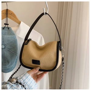 Detail of beige woven straw texture bag with black leather trim and metal chain strap