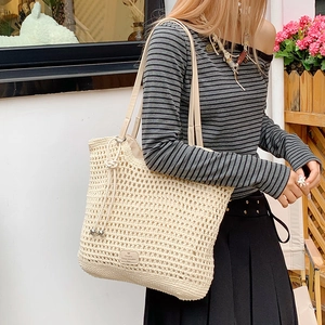 Detail of hollow crochet straw tote featuring drawstring with beads and leather logo patch