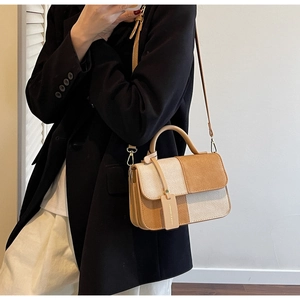 Detail showing the cream woven fabric and brown leather stitching on the handbag