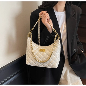 Close-up of a white quilted leather hobo bag with a gold chain strap on a black blazer