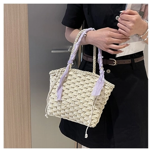 Close-up of beige woven bucket bag with silk scarf handle and pearl charm detail