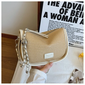 Detail of vintage straw saddle bag with white leather trim and metal chain strap