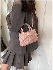 Détail du sac à bandoulière rose brillant avec nœuds en perles et logo argenté chic