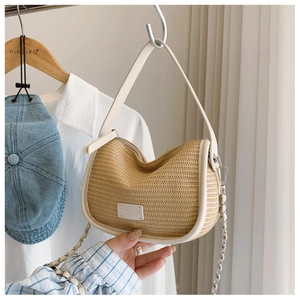 Detail of woven straw shoulder bag featuring white leather trim and a gold chain strap