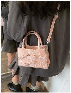 Gros plan d'un sac à main rose avec des nœuds décoratifs, des perles et un logo en métal