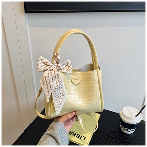 Détail du sac à main beige motif crocodile avec foulard en soie et logo sur bureau moderne