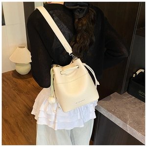 Detail of off-white lychee grain leather bucket bag with drawstring and flower charm