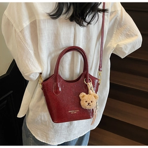 Dettaglio della borsa tote bordeaux lucida con ciondolo orsetto e logo MIKAXIQI