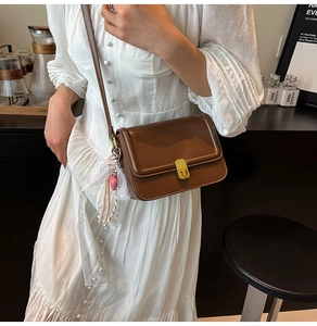 Close-up of dark brown PU leather crossbody bag with golden lock and lace heart charm