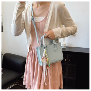 Detail of light blue lychee pattern mini bag with Love Is Eternal rainbow tassel