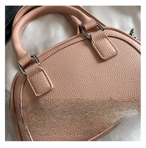 Gros plan du sac à main rose en cuir grainé avec boucles argentées et détails embossés