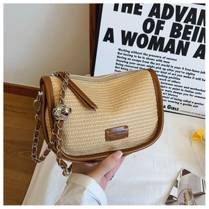 Detail of straw woven saddle bag with leather trim and silver chain shoulder strap