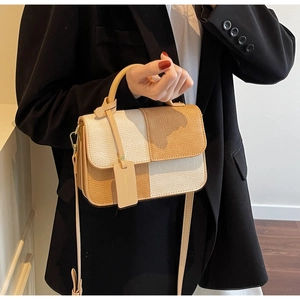 Side view of a minimalist two-tone leather crossbody bag with beige and brown patchwork