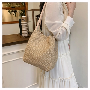 Close-up of hand-woven straw tote bag with delicate texture and dual shoulder straps