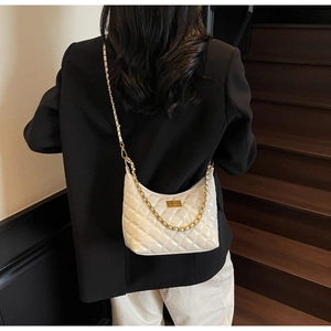 Detail of white quilted hobo bag featuring glossy leather and elegant gold chain strap